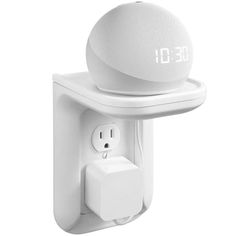 an alarm clock mounted to the side of a white wall outlet with a plug in it