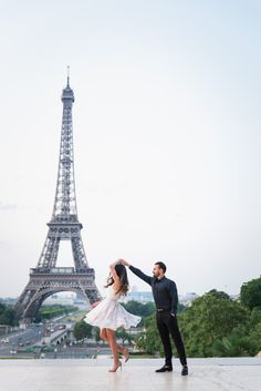 a man and woman dancing in front of the eiffel tower