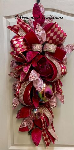 Add a burst of color and festive elegance to your home this holiday season with our Pink & Red Christmas Teardrop Swag Wreath. Perfect to take you through Valentines day as well!  This gorgeous wreath is handcrafted with shimmering iridescent ornaments, luxurious jeweled velvet ribbons, designers gems and beaded leaves in shades of pink. Its unique teardrop shape makes it a striking addition to any front door, entryway, or living room decor, instantly bringing warmth and holiday cheer to your sp Red Wreath Christmas, Front Door Luxury, Iridescent Ornaments, Pink Red Christmas, Christmas Wreath Pink, Pink And Red Christmas, Front Door Pink, Pink Christmas Wreath, Beaded Leaves