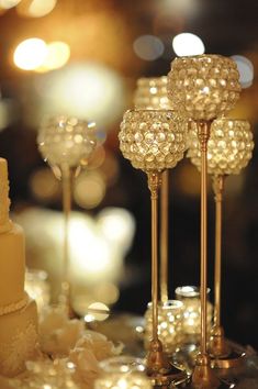 a table topped with lots of gold and white cake next to tall candlesticks