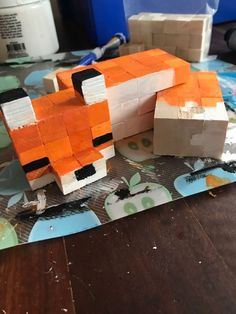 an orange and white animal made out of construction paper on top of a wooden table