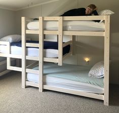 a woman laying on top of a bunk bed in a room with two other bunk beds