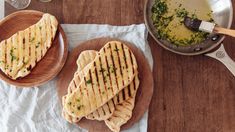 two panini sandwiches sitting on top of wooden plates next to wine glasses and utensils