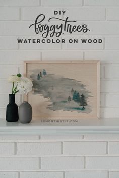 two vases are sitting on top of a mantle in front of a sign that says foggy trees watercolor on wood