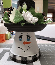 a white hat with green leaves and berries on it sitting on top of a table