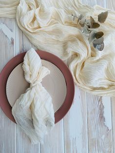 a plate with two pieces of white cloth on top of it next to a napkin