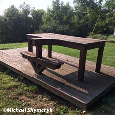 a picnic table on a wooden platform in the grass