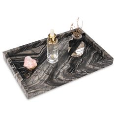 a marbled tray with two bottles and a pink rock on the bottom is shown