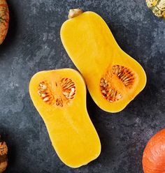 two pumpkins cut in half on a table with other fruits and vegetables around them