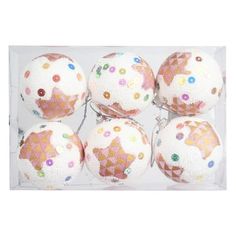 four white and pink christmas balls with stars on them in a package, one is filled with confetti sprinkles