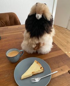 a stuffed animal sitting on top of a table next to a slice of cheesecake