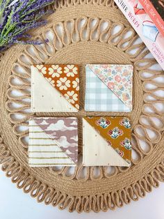 four small pieces of fabric sitting on top of a wicker basket next to books