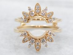 two gold rings with white diamonds on each ring and one has a leaf design in the middle