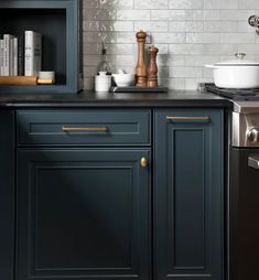 a kitchen with black cabinets and white subway tile backsplash, gold pulls on the cabinet doors