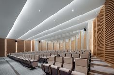 an empty auditorium with rows of chairs facing the wall and ceiling lights on either side