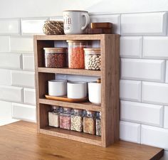 a wooden shelf filled with lots of different types of spices and jars on top of a table