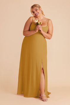 a woman in a yellow dress holding a flower and smiling at the camera while wearing sandals