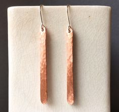 These rustic hammered copper bar earrings are made from recycled 10 gauge copper wire that is hand formed and textured by hammering. The copper is drilled at the top and my own 20 gauge sterling silver ear wires are added. These are a shorter version of my other copper bar earrings and are approximately 1 7/8" long. Earrings come on a Willy Wires card and are packaged in a purple kraft jewelry box. Copper Bar, Hammered Copper, Bar Earrings, Copper Earrings, Earrings Sterling Silver, Long Earrings, Copper Wire, Ear Wires, Jewelry Earrings Dangle