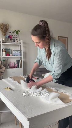 a woman sanding on top of a white table