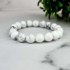 Imagine a piece of jewelry that not only adds a touch of elegance but also tells a story of mystical adventures and bohemian wanderlust. Our Enchanted White Howlite Boho Bead Bracelet is just that! Inspired by the calming aura of White Howlite and the free-spirited essence of bohemian fashion, this bracelet is crafted to perfection. Origin Story: The idea for this bracelet came from a serene walk through a mystical forest, where the shimmering white stones seemed to whisper tales of ancient wisd Adjustable White Spiritual Bracelets, White Round Jewelry For Friendship, Elegant White Crystal Friendship Bracelet, Elegant White Crystal Bracelet For Friendship, Spiritual White Beaded Bangle Bracelet, White Natural Stone Bracelets, Hand-strung White Jewelry As A Gift, White Natural Stone Round Bracelets, Hand-strung White Jewelry For Gift