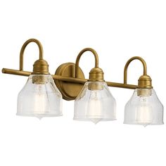 three light bathroom fixture in an antique brass finish with clear glass shades on the sides