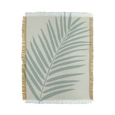 a green and white palm leaf rug with fringes on the bottom, against a white background