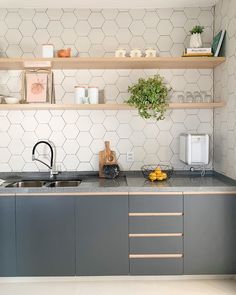 a kitchen with gray cabinets and white hexagonal tile backsplash, shelves above the sink