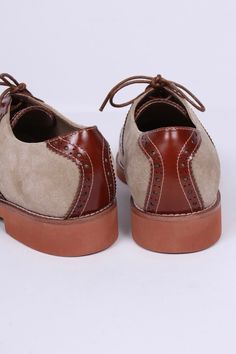 Casual two-tone 1950s-style oxford/saddle shoes with brogue pattern. These two-tone, 1950s-inspired, casual everyday oxfords feature an almond-shaped toe cap. The shoe is made of suede and features cognac brown full-grain leather with a brogue pattern on the backstay and around the vamp. The outsole is crafted from lightweight rubber with white stitching on the welt. These shoes were initially men's shoes. But here, it is also made for women. The shoes have a casual, sporty, and authentic 50s lo Women’s Oxford Shoes, Vintage Brown Lace-up Shoes With Rubber Sole, Brown Wingtip Lace-up Oxford Shoes, Retro Brown Leather Lace-up Shoes, Retro Brogue Lace-up Shoes With Round Toe, Retro Lace-up Shoes With Brogue Detailing, Retro Almond Toe Oxfords For Workwear, Retro Oxford Lace-up Shoes With Brogue Detailing, Retro Oxfords With Brogue Detailing And Round Toe