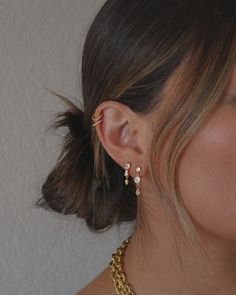 a close up of a woman's face wearing a gold necklace and earring