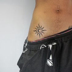 a man with a sun tattoo on his stomach is standing in front of a white wall