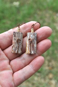 If you love natural jewelry items, then check out these natural stone bead earrings. I used large jasper beads (they look a bit like petrified wood, but are not) with small wood beads for the design, then used tarnish resistant antique copper wire to hold the beads and created a spiral embellishment. The ear wires are created from the same tarnish resistant wire. Natural stone and handmade items are unique in that no two are exactly alike.  These earth tone earrings will enhance so many other colors, they will make a fabulous addition to your natural jewelry collection or a thoughtful gift for someone special! Earring length from top of ear wire - appx 2.2 inches Length and width of the jasper beads - appx 1.15 x 0.54 inches They are very lightweight Thank you for shopping with small busin Brown Rectangular Bohemian Earrings, Bohemian Brown Rectangular Earrings, Copper Wire Earrings, Natural Earrings, Earth Jewelry, Driftwood Jewelry, Natural Stone Earrings, Nature Earrings, Natural Jewelry