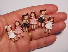 five little dolls are sitting in the palm of someone's hand, all wearing dresses