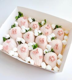 a white box filled with pink and white chocolate covered strawberries next to each other