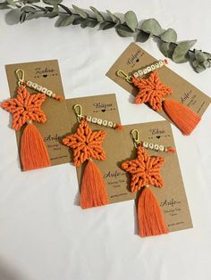 four orange tasseled earrings with gold accents on top of a white tablecloth