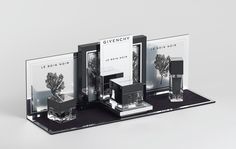 an assortment of perfumes displayed on a black and white display case with the word givenchy printed on it