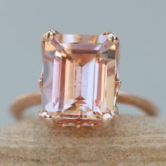 an orange and white diamond ring sitting on top of a piece of stone with gold accents