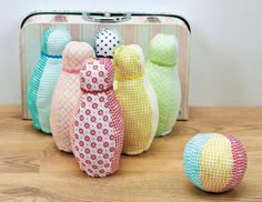 four colorfully painted wooden dolls sitting in front of a suitcase