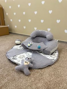 a teddy bear laying on the floor next to some blankets and pillows in a room with hearts painted on the walls