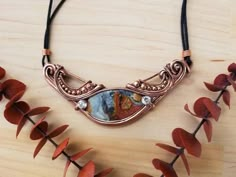 a close up of a necklace on a wooden surface with flowers in the foreground