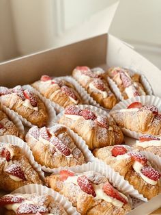 a box filled with lots of pastries covered in powdered sugar and strawberries