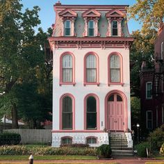 an old pink and white house in the middle of town