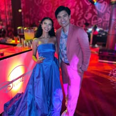 a man and woman standing next to each other in front of a neon sign at a party