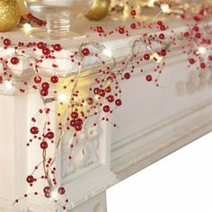 a white mantle with red berries and gold ornaments