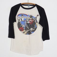 a white and black shirt with an image of the band fleetwood on it hanging from a wooden hanger