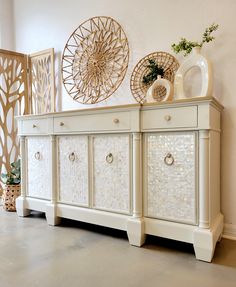 a white dresser with drawers and vases on top