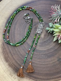 This gorgeous necklace with two tassels is designed with a unique look. It is made from a mix of czech glass beads in different shades of green and shapes. In between the purple beads are brown agate beads for a beautiful contrast. All metal components are silver plated. The pendant connector is vintage inspired rectangle shape that is about 1.25 inches long. The entire length of the pendant with tassels is 6.25 inches long. This necklace is similiar to a lariat style. The necklace length is 27. Tassel Necklace Boho, Brown Agate, Purple Beads, Grey Beads, Different Shades Of Green, Chain Extenders, Shell Necklaces, Agate Beads, Gorgeous Necklaces