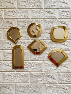 five mirrors mounted to the side of a white brick wall