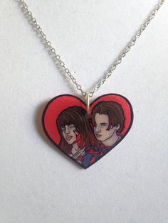 a heart shaped necklace with two people on it