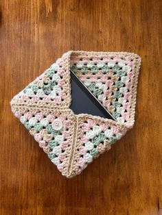 a small crocheted dishcloth on a wooden table with a black tablet in it