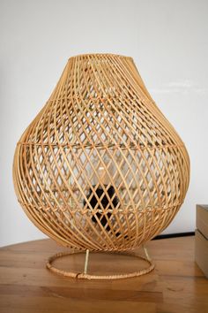 a wicker vase sitting on top of a wooden table next to a small box